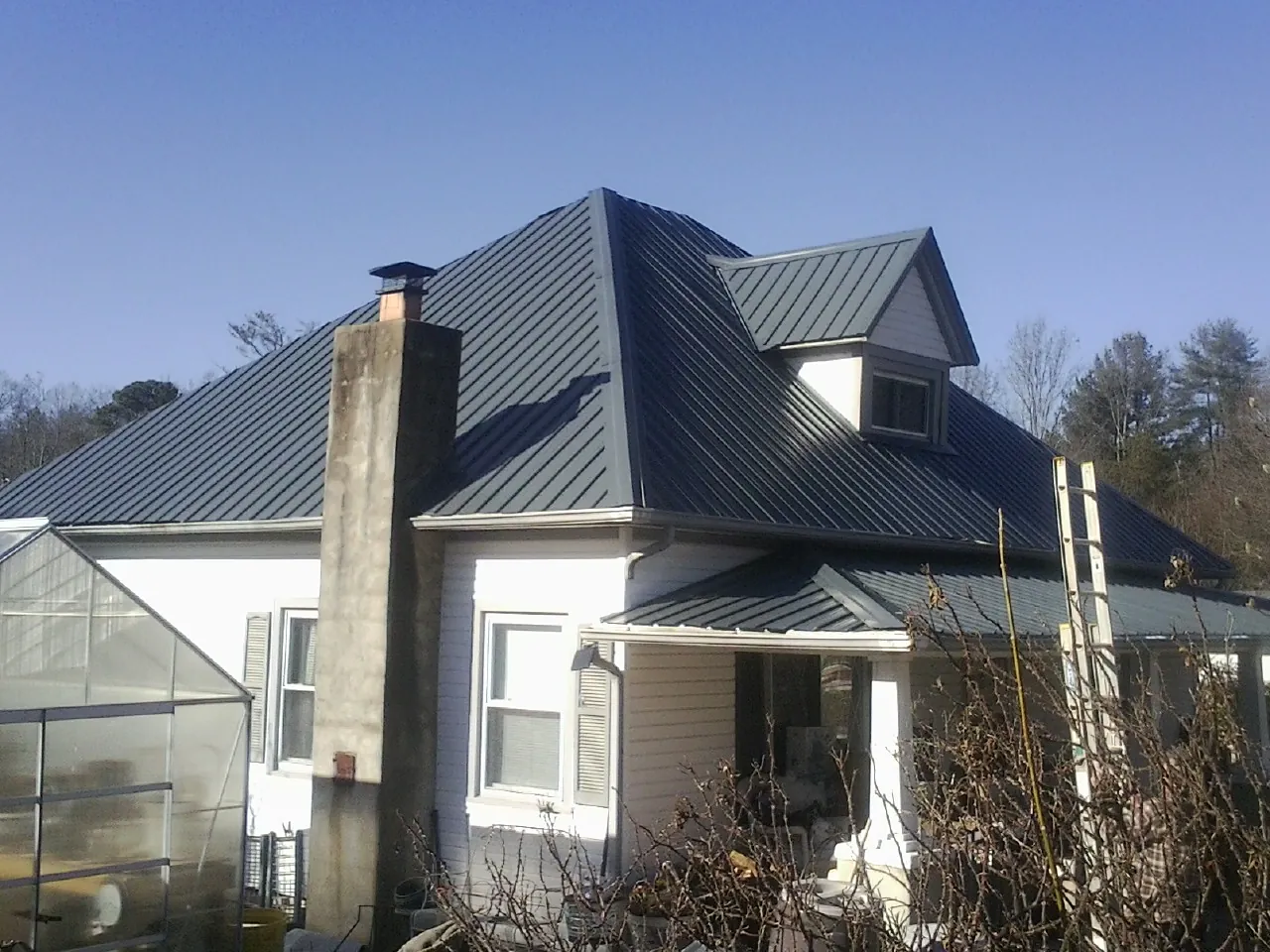 Dark blue standing seam metal roof on a white farmhouse with dormer — Slate & Tile Roof Repair by Roofing Brothers in Winneconne