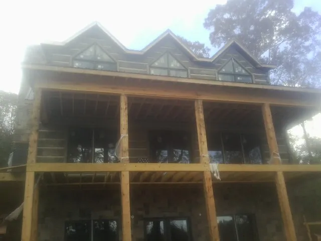 Dormers and porch framing on a large log home under construction — Roof Coating work by our crew in Winneconne