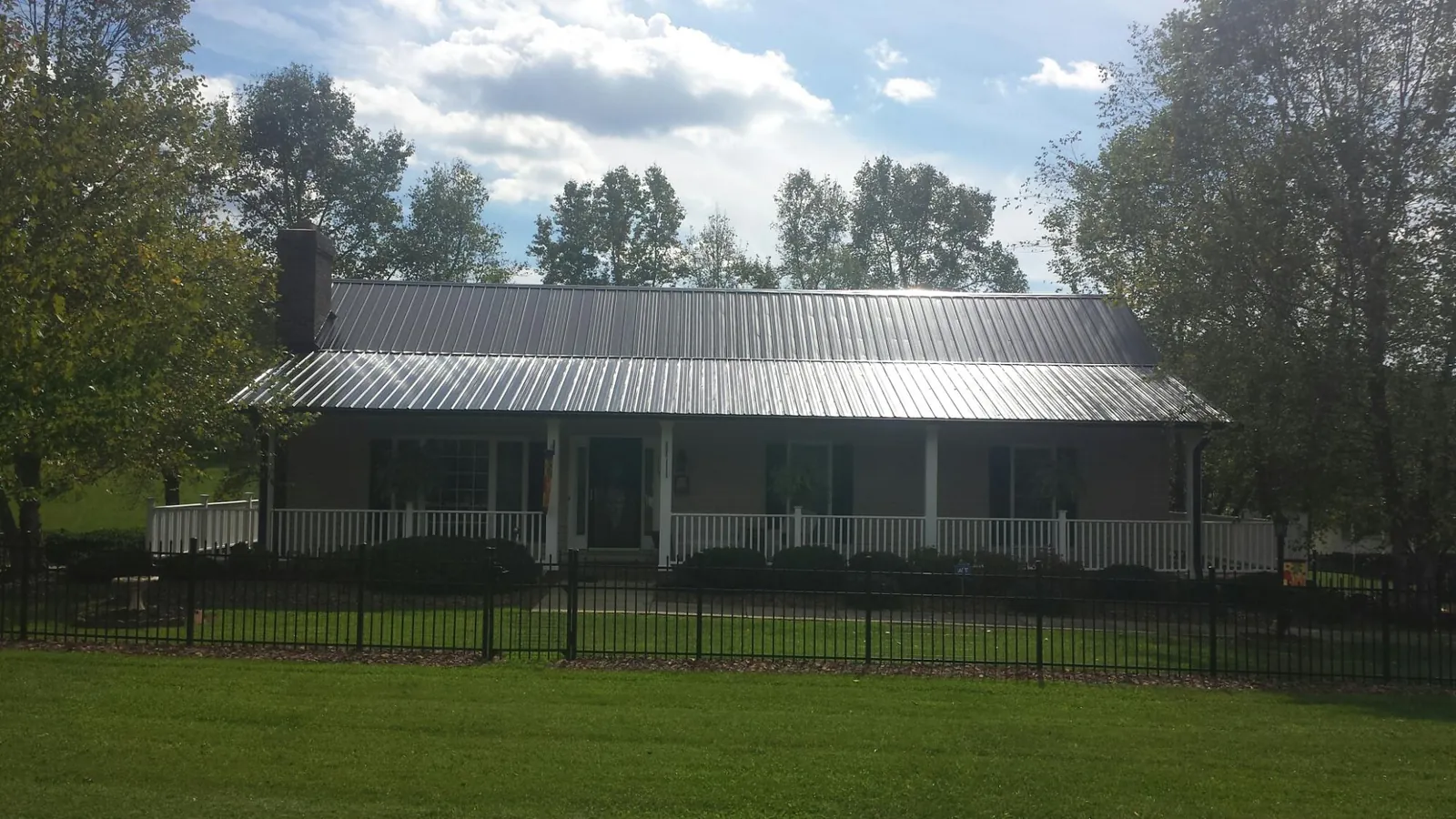 Gray metal roof on a brick ranch with a full width front porch — Gutter Guard Installation work by our crew in Winneconne