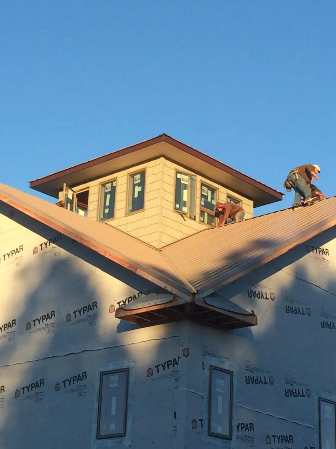 Roofers working around a rooftop cupola on a new metal roof at sunset — Roof Waterproofing in Winneconne by Roofing Brothers